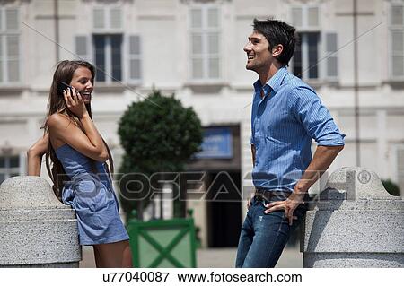 Young couple standing outdoors, young woman using smartphone, Turin, Piedmont, Italy View Large Photo Image Stock Photo - Young couple standing outdoors, young woman using smartphone, Turin, Piedmont, Italy. Fotosearch