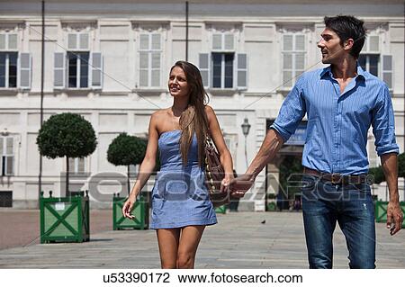 Stock Image - Young couple walking outdoors, hand in hand, Turin, Piedmont, Italy. Fotosearch