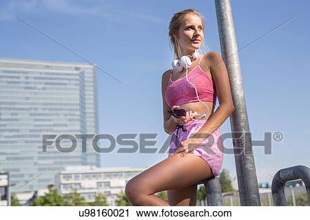 Stock Image - Young female runner in city looking over her shoulder. Fotosearch
