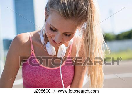 Stock Photo - Young female runner in city parking lot looking down. Fotosearch