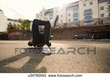 Stock Photography - Young man laying on skateboard, relaxing, Bristol, UK. Fotosearch