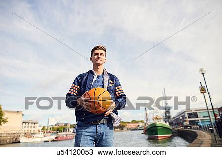 Young man near river, holding basketball, Bristol, UK View Large Photo Image Stock Image - Young man near river, holding basketball, Bristol, UK. Fotosearch