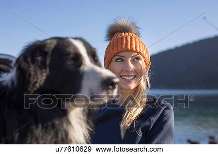 Stock Photo - Young woman and dog on lakeside in Bavarian Alps. Fotosearch