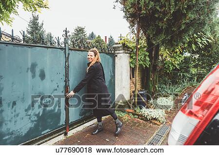 Young woman closing driveway gates View Large Photo Image Stock Photo - Young woman closing driveway gates. Fotosearch