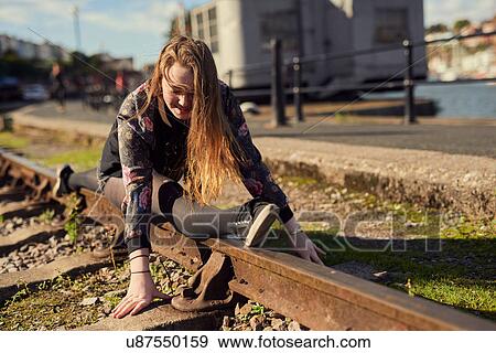 Stock Photo - Young woman doing splits, balancing on train track, Bristol, UK. Fotosearch
