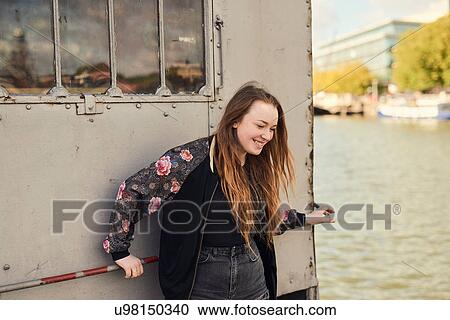Stock Image - Young woman fooling around beside river, Bristol, UK. Fotosearch