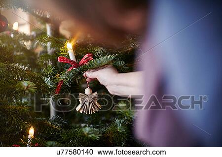 Stock Image - Young woman hanging decoration on Christmas tree, close-up. Fotosearch