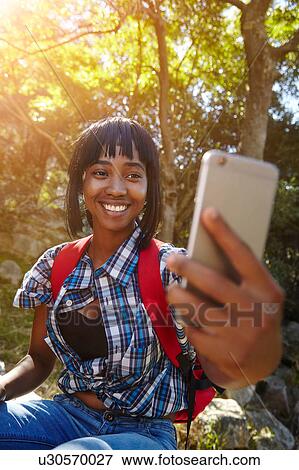 Young woman in forest, using smartphone, having video call, Cape Town, South Africa View Large Photo Image Stock Photo - Young woman in forest, using smartphone, having video call, Cape Town, South Africa. Fotosearch