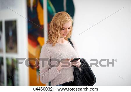 Young woman looking at smartphone View Large Photo Image Stock Image - Young woman looking at smartphone. Fotosearch