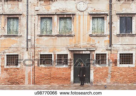 Stock Photograph - Young woman looking over her shoulder from old doorway, Venice, Italy. Fotosearch