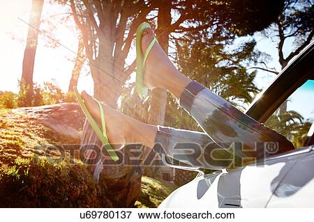Young woman lying in car, legs dangling out of car window View Large Photo Image Stock Photo - Young woman lying in car, legs dangling out of car window. Fotosearch