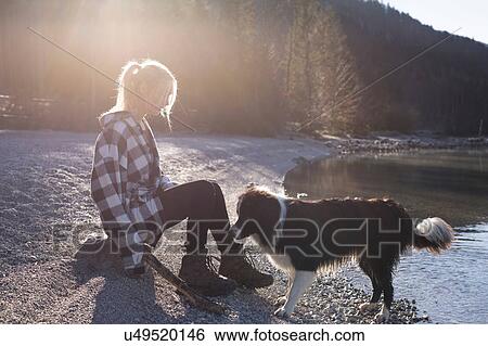 Young woman on lakeside playing with dog in Bavarian Alps View Large Photo Image Stock Photograph - Young woman on lakeside playing with dog in Bavarian Alps. Fotosearch