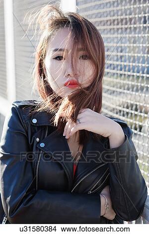 Picture - Young woman posing, fence in background. Fotosearch