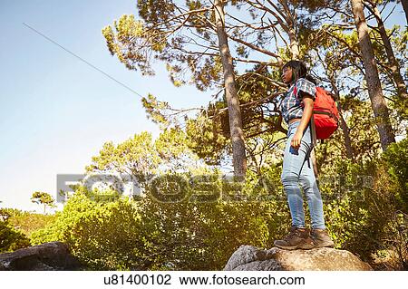 Stock Image - Young woman standing on rock, looking at view, Cape Town, South Africa. Fotosearch