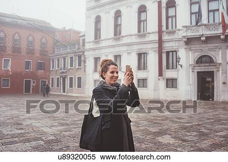 Young woman taking smartphone selfie in misty square, Venice, Italy View Large Photo Image Stock Photography - Young woman taking smartphone selfie in misty square, Venice, Italy. Fotosearch