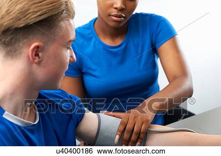 Stock Photograph - Young woman taking young man's blood pressure. Fotosearch