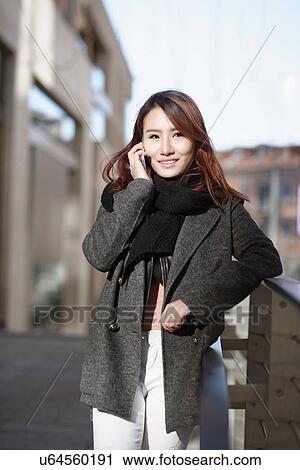 Stock Image - Young woman using mobile phone, Milan, Italy. Fotosearch