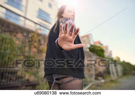 Stock Photo - Young woman walking outdoors, holding hand to camera, rear view, Bristol, UK. Fotosearch