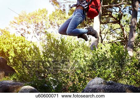 Young woman, wearing backpack, jumping in air, low section View Large Photo Image Stock Image - Young woman, wearing backpack, jumping in air, low section. Fotosearch