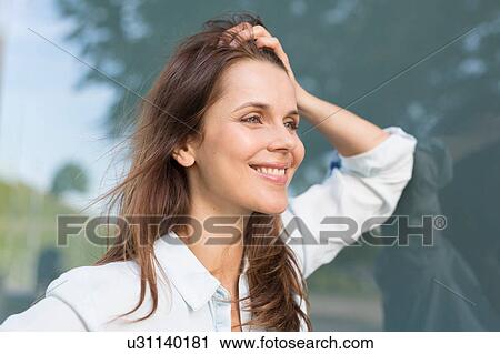 Stock Image - Businesswoman with hand in hair outside airport. Fotosearch