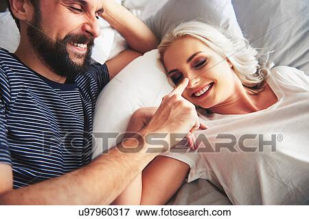 Couple lying in bed, fooling around, man poking woman's nose View Large Photo Image Stock Photo - Couple lying in bed, fooling around, man poking woman's nose. Fotosearch