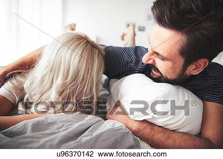 Couple lying on bed, man tickling woman View Large Photo Image Stock Image - Couple lying on bed, man tickling woman. Fotosearch