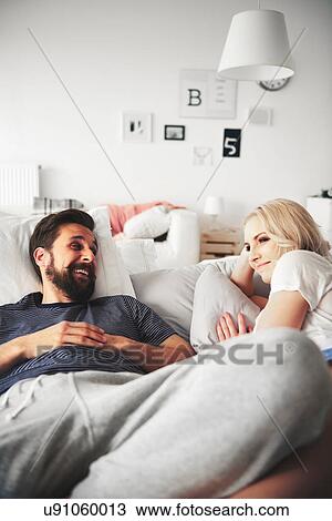 Couple relaxing on bed, smiling View Large Photo Image Stock Image - Couple relaxing on bed, smiling. Fotosearch