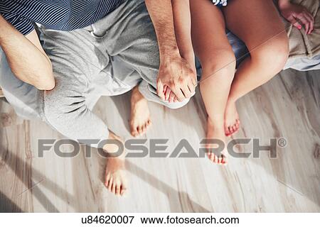 Couple sitting on edge of bed, holding hands, overhead view View Large Photo Image Stock Photo - Couple sitting on edge of bed, holding hands, overhead view. Fotosearch