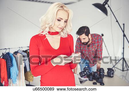 Stock Photo - Female model looking at smartphone in studio photo shoot. Fotosearch