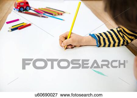 Hand of boy lying on floor drawing on long paper View Large Photo Image Stock Photo - Hand of boy lying on floor drawing on long paper. Fotosearch