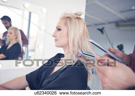 Stock Photograph - Hands of hairdresser holding hair straighteners for model at photo shoot. Fotosearch