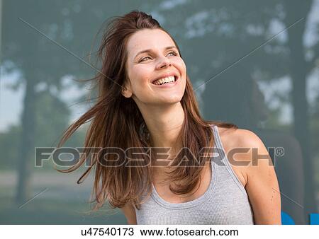 Stock Image - Happy mid adult woman outside glass fronted building. Fotosearch