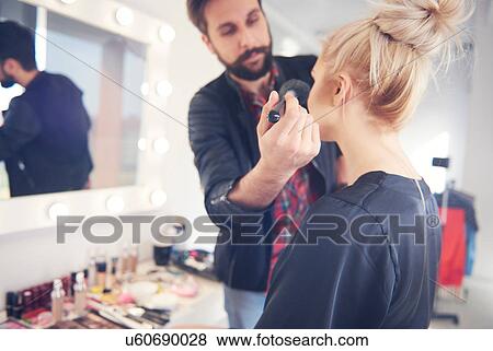 Stock Photo - Male make up artist applying blusher to model for photo shoot. Fotosearch