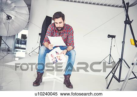 Stock Photography - Male photographer looking at photographs in studio. Fotosearch