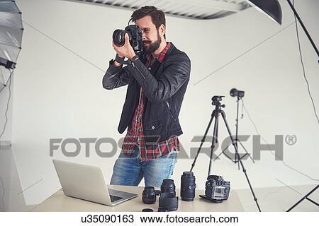 Stock Image - Male photographer testing digital SLR focus for studio photo. Fotosearch
