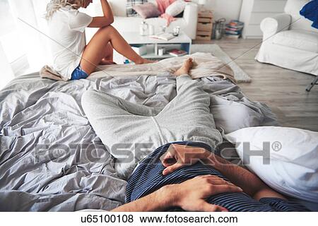 Man lying on bed, woman sitting at end of bed View Large Photo Image Stock Photo - Man lying on bed, woman sitting at end of bed. Fotosearch