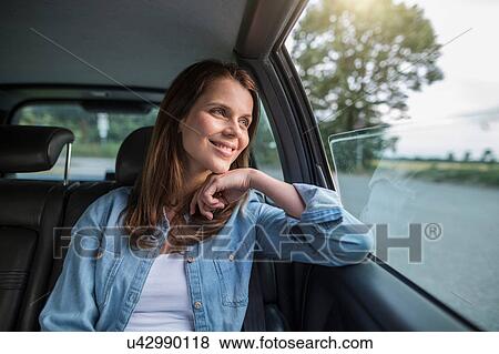 Stock Photo - Mid adult woman looking through car window from front seat. Fotosearch