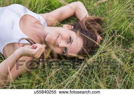 Stock Photography - Mid adult woman lying on back in grass. Fotosearch