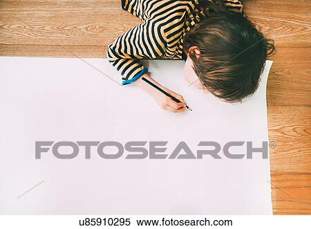 Overhead view of boy drawing on large paper on floor View Large Photo Image Stock Photography - Overhead view of boy drawing on large paper on floor. Fotosearch