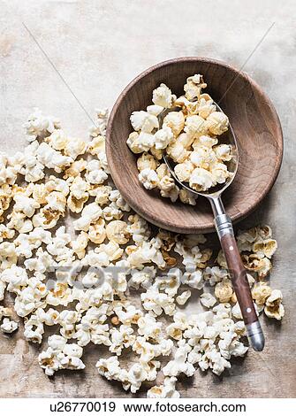 Stock Photo - Popcorn in wooden bowl with metal scoop, overhead view. Fotosearch
