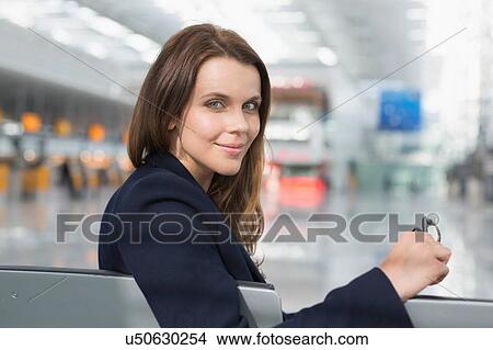 Portrait of businesswoman looking over her shoulder in airport departure lounge View Large Photo Image Picture - Portrait of businesswoman looking over her shoulder in airport departure lounge. Fotosearch