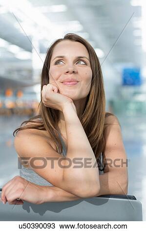 Stock Image - Portrait of businesswoman looking up in airport departure lounge. Fotosearch