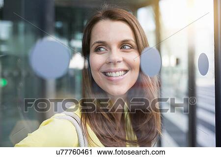 Stock Image - Portrait of businesswoman through airport glass door. Fotosearch