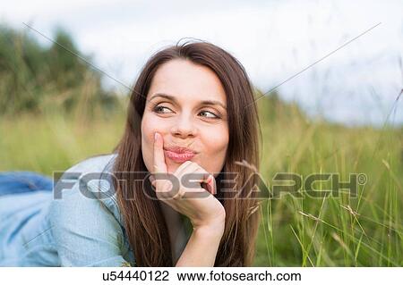 Stock Image - Portrait of woman lying in field looking sideways. Fotosearch