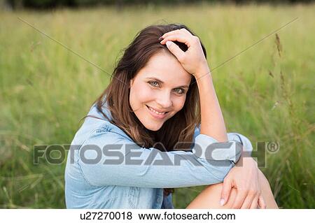 Stock Photo - Portrait of woman sitting in field. Fotosearch