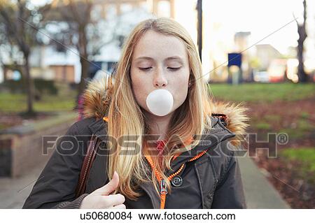 Picture - Portrait of young woman, outdoors, blowing bubble with bubblegum. Fotosearch