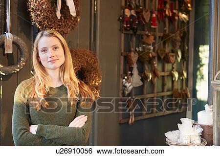 Portrait of young woman standing in shop doorway, arms folded View Large Photo Image Stock Photograph - Portrait of young woman standing in shop doorway, arms folded. Fotosearch