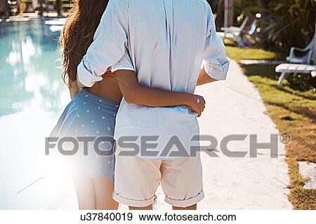 Rear mid section view of young couple embracing at poolside, Koh Samui, Thailand View Large Photo Image Stock Photo - Rear mid section view of young couple embracing at poolside, Koh Samui, Thailand. Fotosearch
