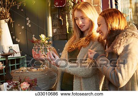 Two female friends looking at flowers, outside shop View Large Photo Image Stock Photograph - Two female friends looking at flowers, outside shop. Fotosearch