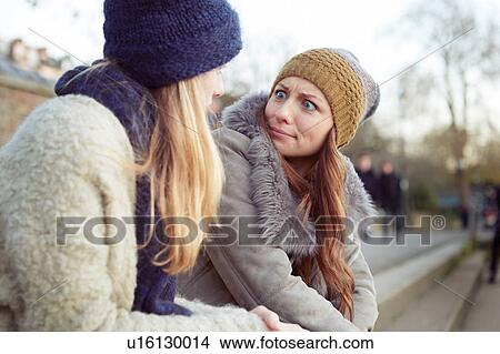 Two female friends outdoors, sitting on steps, fooling around, pulling faces View Large Photo Image Picture - Two female friends outdoors, sitting on steps, fooling around, pulling faces. Fotosearch